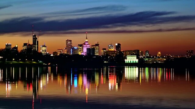 Tranquil evening skyline of Warsaw, capital of Poland river view, city downtown with reflection in water.