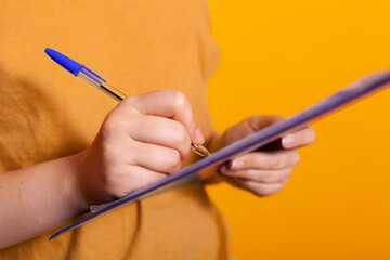 Close up of hand holding pen and writing on clipboard papers for information. Caucasian person signing notebook documents and taking notes to do paperwork planning. Adult with journal