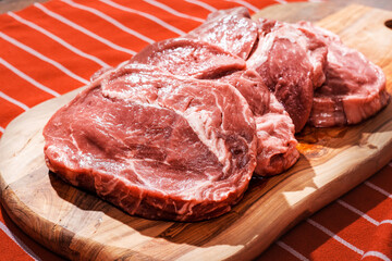 Four rib eye steaks on a wooden cutting board on a red and white apron. Premium top quality fresh meat. Butcher craft and food supply chain industry.