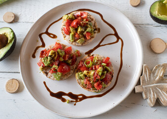 Salad with avocado and tomatoes topped with balsamic dressing and served with brown rice cracker