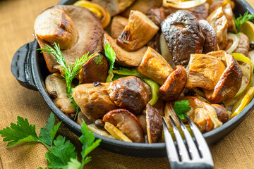 Cooked porcini mushrooms in the frying pan on the wooden table. Top view.