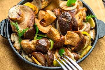 Cooked porcini mushrooms in the frying pan on the wooden table. Top view.