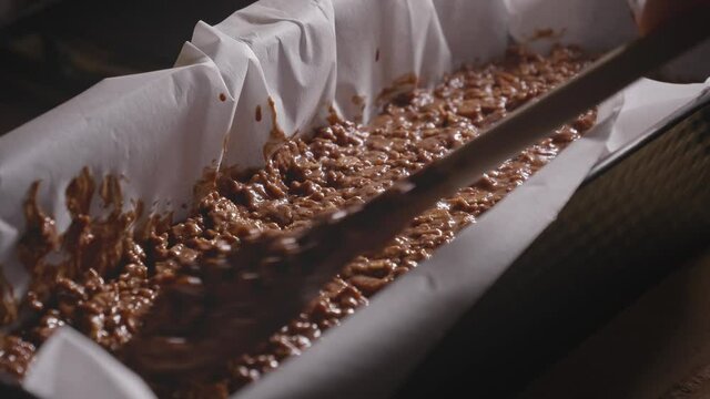 Person is Smoothing a Chocolate Batter in a Cake Pan with a Wooden Spoon, Baking a Chocolate Oat Cake - Steady Shot
