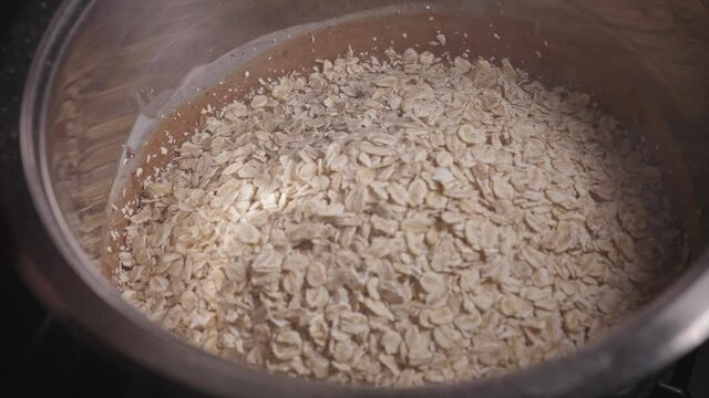 Pouring Oats Into Metal Bowl With Chocolate Batter, Baking a Delicious Chocolate Oat Cake - Steady Shot