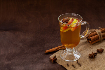 glass of mulled wine with spices. homemade spice apple cider with fresh apples, honey, cinnamon, cardamon, anise, clove. hot fruit tea on the wooden table. Christmas drinks. traditional drinks.