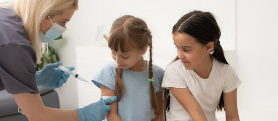 nurse giving vaccination injection to little girl patient