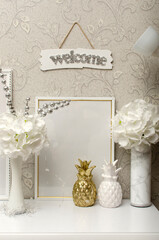 Still life with artificial flowers in vases, photo frame and decorative pineapples. Home decor	