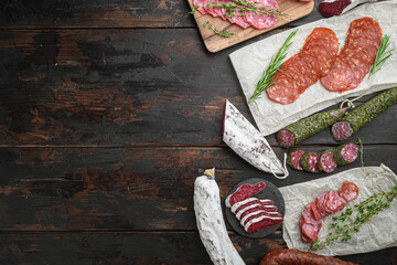 Variety of dry cured  chorizo, fuet and other sausages cut in slices with herbs on old wooden...
