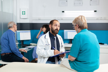 Fototapeta premium Retired patient discussing with doctor about osteopathy and physical injury at healthcare consultation. Medic and aged woman having conversation to exercise for bones recovery.
