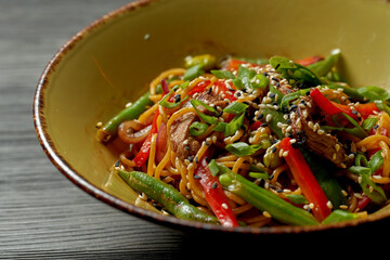 Asian noodles with beef, vegetables, sesame seeds and teriyaki sauce. Street food - noodles wok