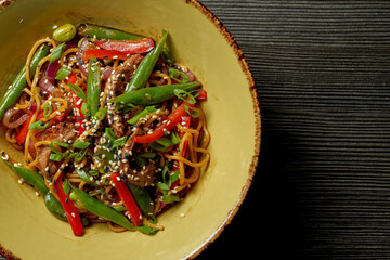 Asian noodles with beef, vegetables, sesame seeds and teriyaki sauce. Street food - noodles wok