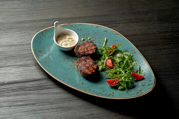 Grilled beef medallions with salad and white sauce.