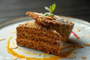 Portion of sweet waffle cake with condensed milk in a white plate on a wooden background