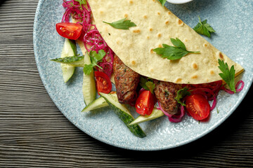 Classic Turkish dish - grilled lula kebab in pita bread with fresh vegetables. Selective focus
