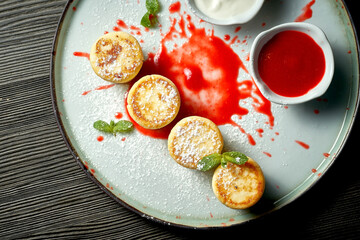 An ideal breakfast - Cottage cheese pancakes with cream sauce in a white plate. Ukrainian syrniki