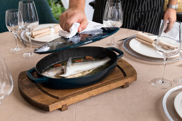 Obraz na płótnie Canvas dorado fish in pan prepared for table in restaurant. pike perch defocused