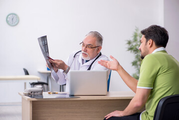 Obraz premium Young man visiting old male doctor radiologist