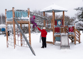 A woman with a child, Caucasian 2 people, walk and play on the playground on a winter day.