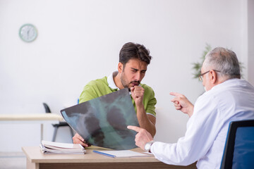 Obraz premium Young man visiting old male doctor radiologist