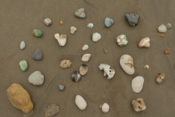 Group of stones of different colors and textures on an empty beach during the day