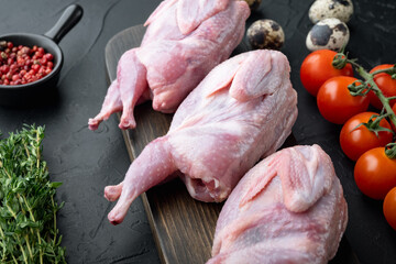 Fresh  raw meat quails ready for cooking, on black textured background