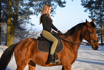 Obraz premium Young girl with horse on winter forest road