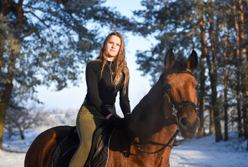 Fototapeta premium Young girl with horse on winter forest road