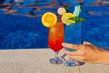Blue Lagoon Beach Cocktail and Sex on the beach Cocktail in front of a blue swimming pool. summer cocktail with copy space