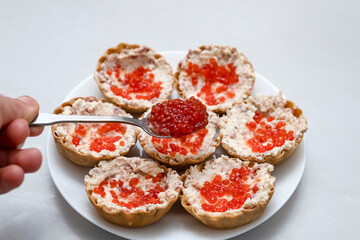 Spoon red caviar on top of baskets with pate and red caviar.