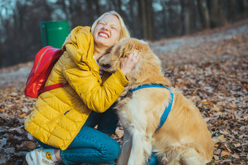 Happy woman enjoying walk in nature and embracing pet dog in forest park. Woman with dog on a walk outdoors in forest, resting. Young woman with dog.