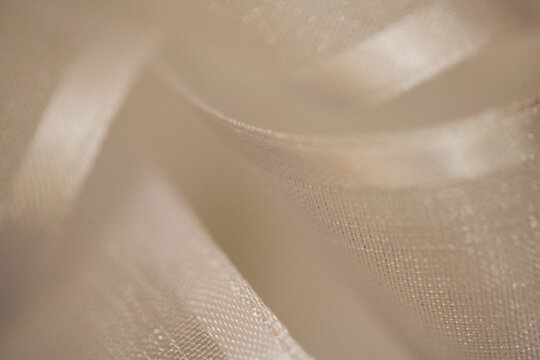 Defocused sparkling white curling party ribbon creates an abstract, textured, bokeh background. Full frame, extreme close-up.