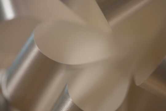 Defocused sparkling silver white curling party ribbon creates an abstract, textured, bokeh background. Full frame, extreme close-up.