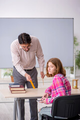 Young male teacher and redhead girl in the classroom