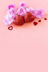 Valentines, love and wedding concept. Lilac violet flowers and red hearts on pink background. Flat lay, top view. Copy space.