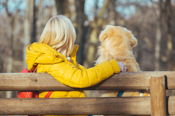 Young girl with her dog in a park. Happy woman sitting with Golden Retriever in a forest. Portrait...