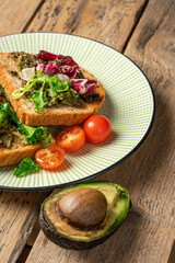 toast with avocado. vegetarian breakfast. Vegan or Vegetarian Toast with mashed avocado, arugula served on wooden board