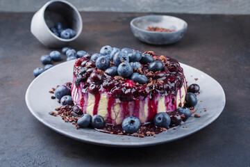 Traditional blueberry cheesecake with fresh berries, compote and chocolate crumbles served as close-up on a design plate with copy space