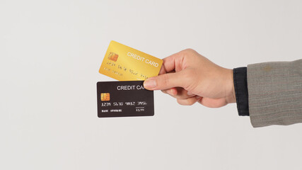 The hand is holding two credit cards and wearing suit. Black and gold color cards on white background.