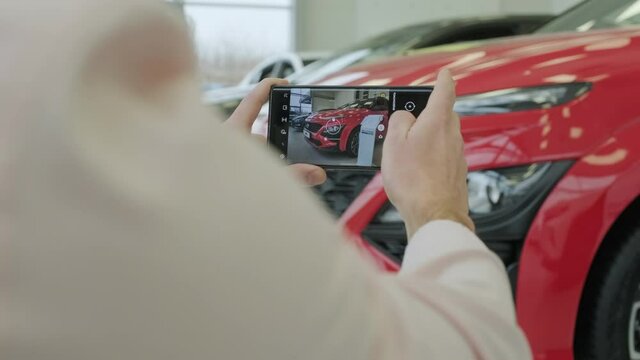 The dealership manager takes pictures of a new car for sale. Car showroom of new prestigious cars.
