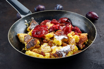 Traditioneller österreichisch Kaiserschmarren mit Zwetschgen und Rosinen serviert als Draufsicht in einer rustikalen Bratpfanne 