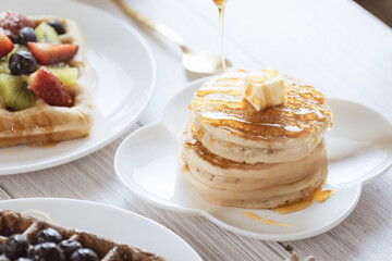 Pancake with butter and honey maple syrup set on white cafe table.