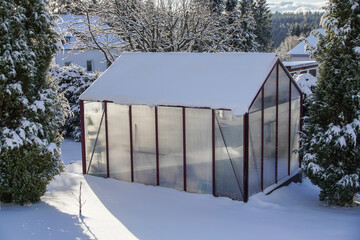 Ein Gew&auml;chshaus im Winter mit viel Schnee im Garte Eigenheim