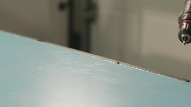 Production of advertising signs in the factory. Screwdriver tightens the screw