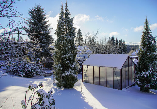Ein Gewächshaus im Winter mit viel Schnee im Garte Eigenheim