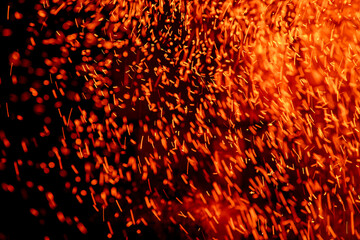 Flying sparks of flame on a dark background abstract image