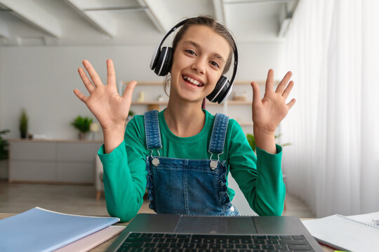 Girl sitting at desk, having video call wearing headphones