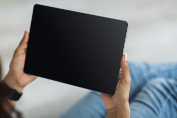 Black woman holding digital tablet with blank screen mockup for application, website or advertisement, empty space