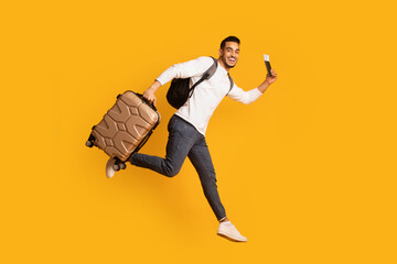 Fototapeta na wymiar Portrait Of Young Happy Arab Man Jumping With Suitcase And Pasport