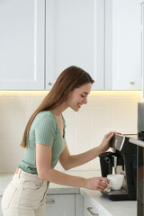 Young woman preparing fresh aromatic coffee with modern machine in kitchen