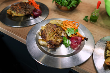 Traditional roasted dry aged veal tenderloin with carrots and potatoes offered as closeup on metal plate.